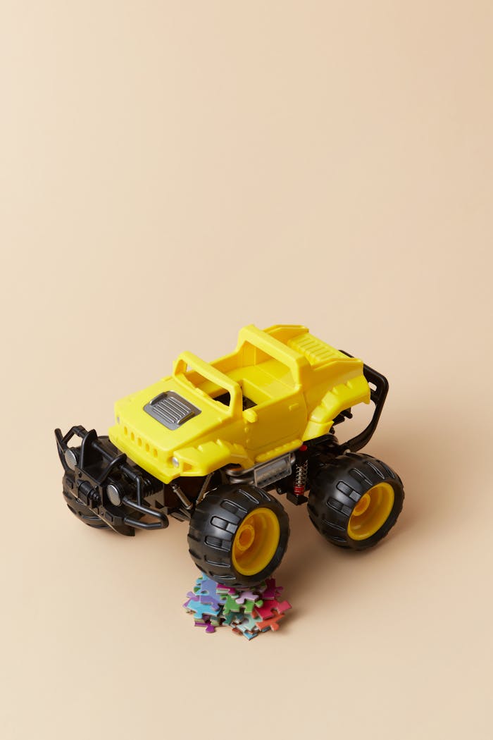 about-us A bright yellow toy truck on a beige surface with colorful puzzle pieces. Perfect for childrens' play concepts.